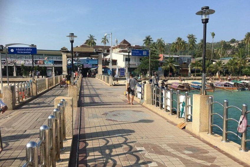 A waterfront promenade with a tiled walkway, metal railings, and a view of boats in the water. 2