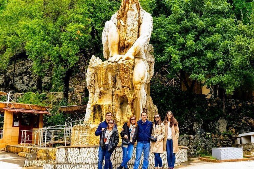 Una gran estatua de piedra de una figura sentada, con un grupo de personas de pie frente a ella. 2