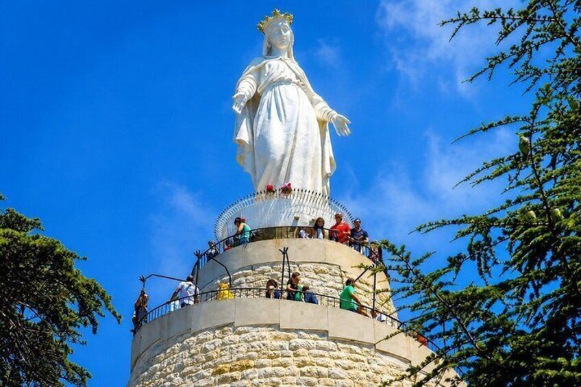 Una estatua blanca de gran tamaño sobre una base de piedra circular, con gente a su alrededor. 3