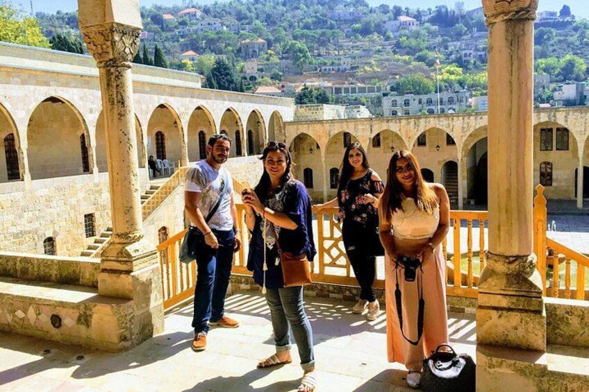 A group of people standing on a stone bridge with arches, overlooking a valley with buildings. 5