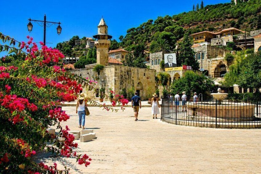 A historic square with a fountain, people walking, and a prominent tower. 3