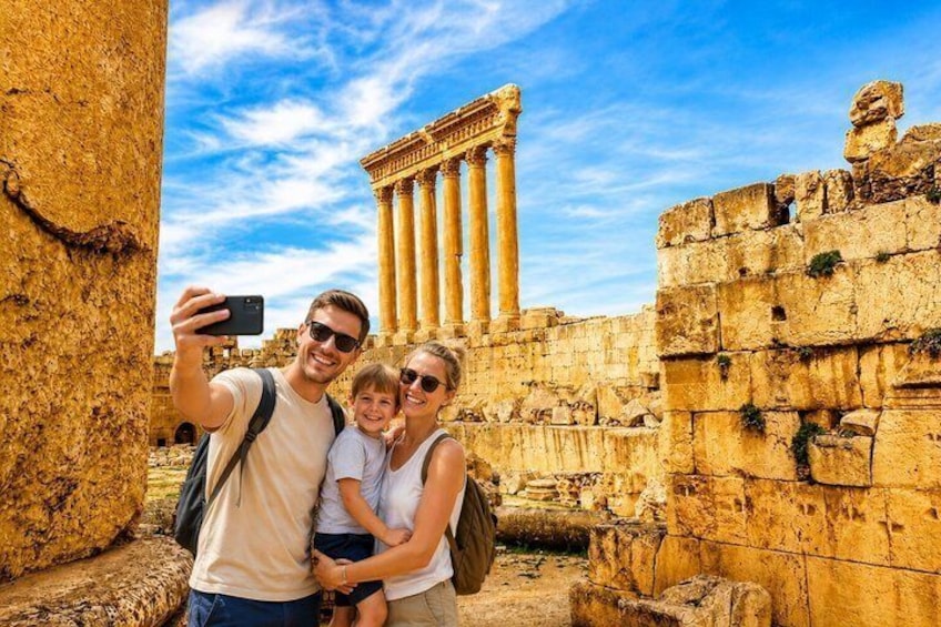 A family taking a selfie with ancient ruins and a temple in the background. 1