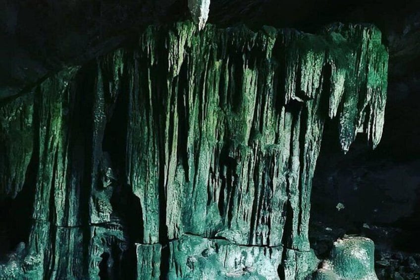 Una grotta con stalattiti verdognole pendenti dal soffitto. 4
