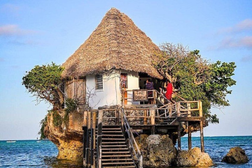 Una casa con tetto di paglia su palafitte, sopra l'acqua, con una scala di legno che vi conduce. 5