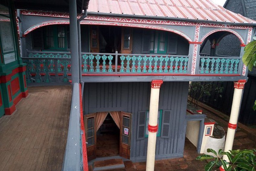 A two-story house with a balcony, decorative railings, and a wooden deck. 4