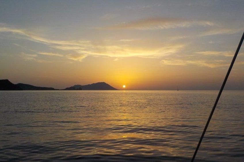 A sunset over a calm sea with a distant landmass. 3