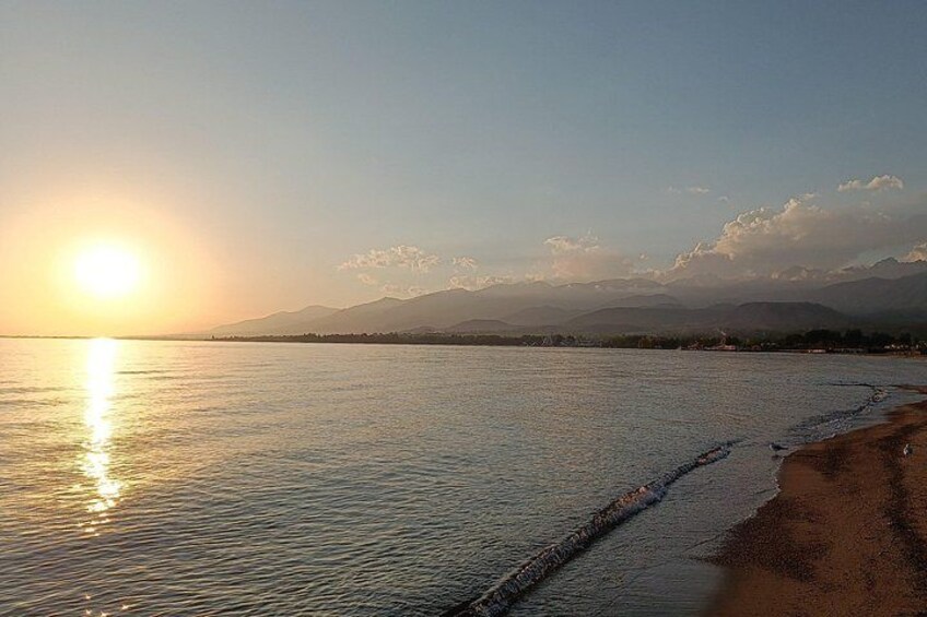 A calm beach at sunset with mountains in the background. 3