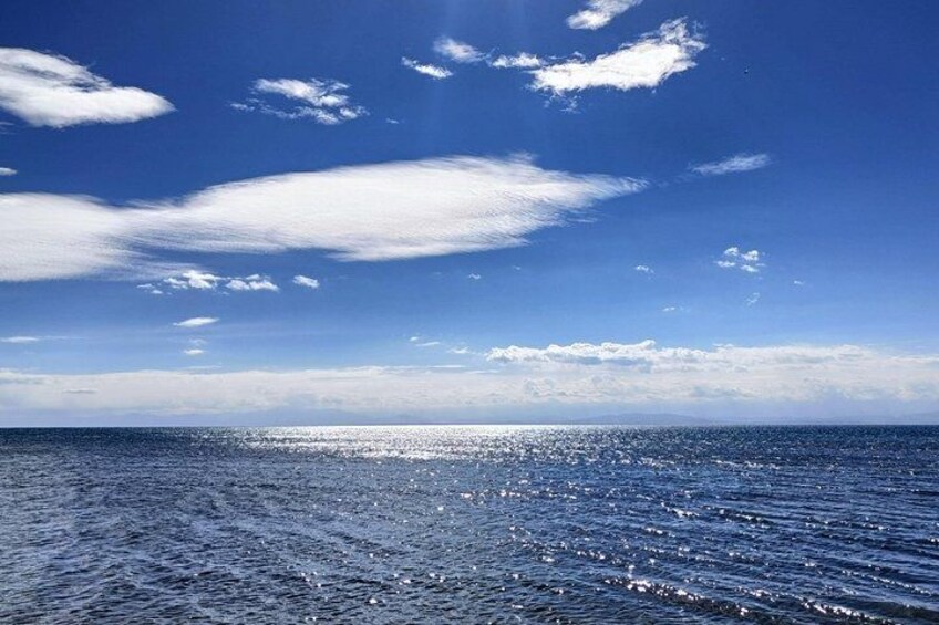 A calm sea under a clear sky with scattered clouds. 5