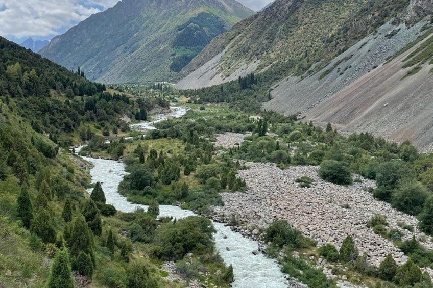 Een rivier die door een bergachtig landschap stroomt, met dichte bossen en rotsachtig terrein. 5