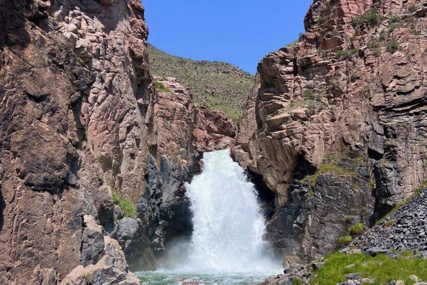 A waterfall cascading down a rocky cliff surrounded by a mountainous landscape. 3