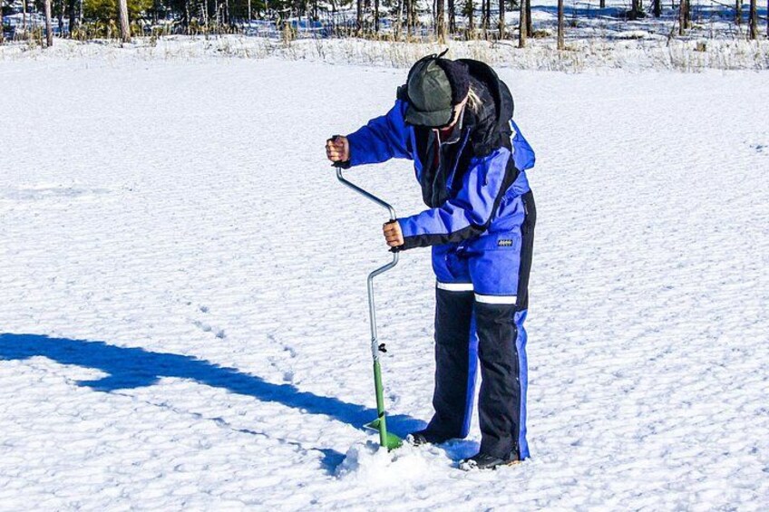 A person in blue winter clothing using a green shovel to dig in the snow. 1