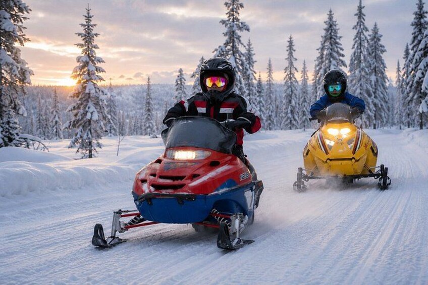 Zwei Schneemobile auf einem verschneiten Pfad, Bäume im Hintergrund. 1