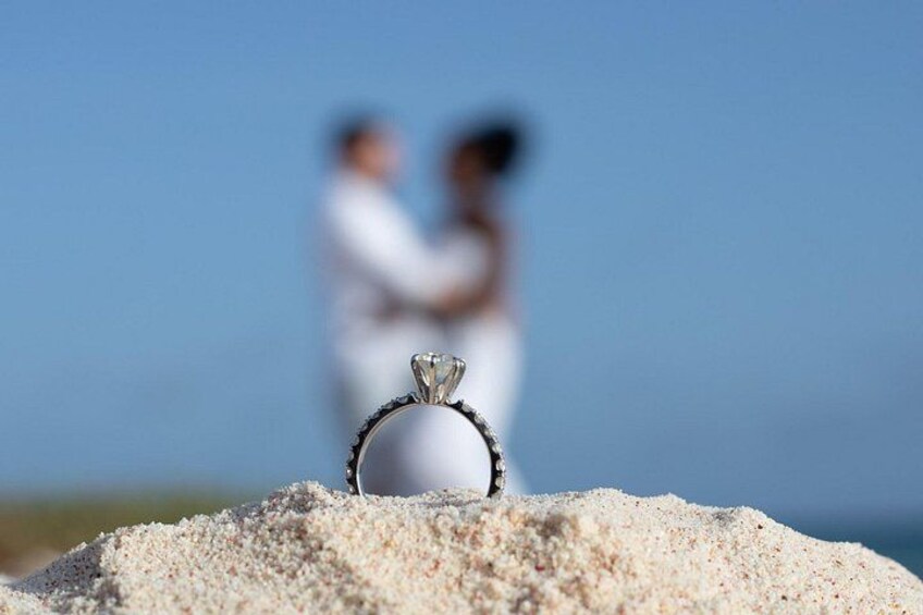 A ring on a pile of sand with a couple in the background. 1