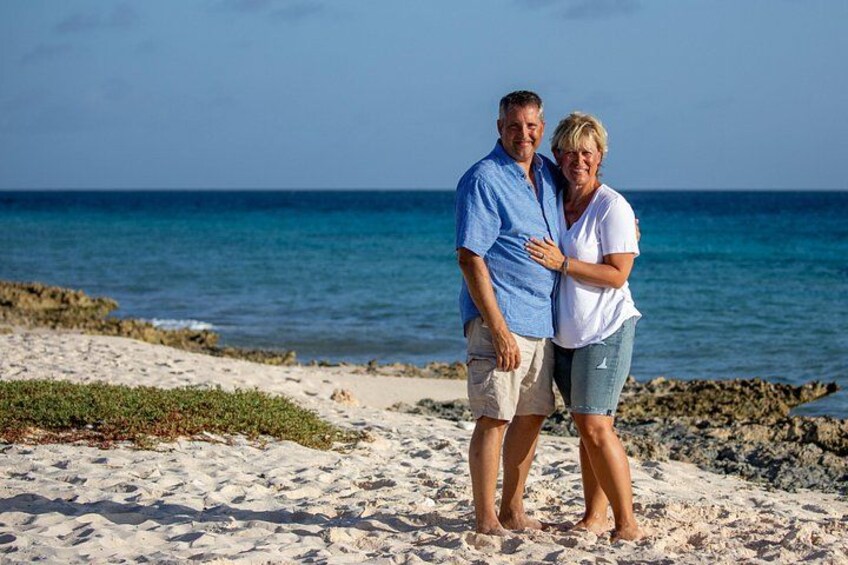 A couple standing on a sandy beach with the ocean in the background. 5