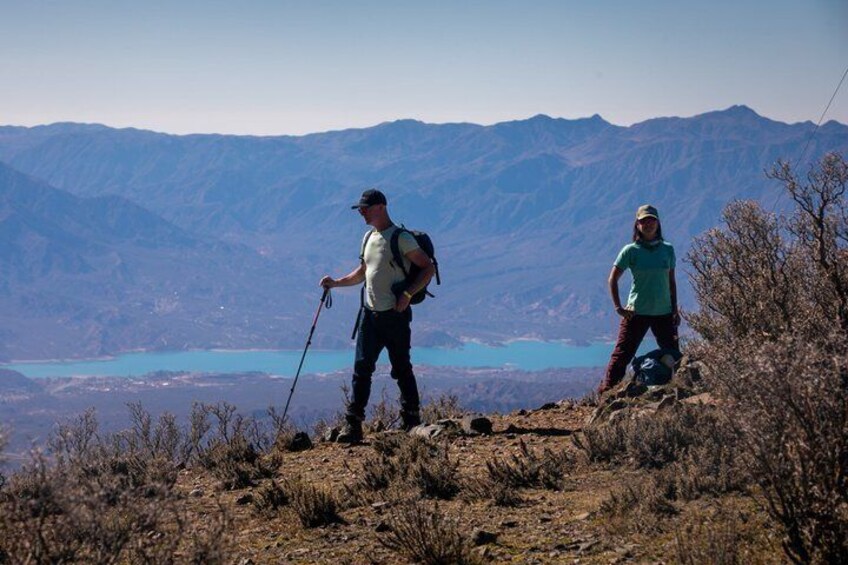 Two hikers on a mountain trail with a lake in the background. 1