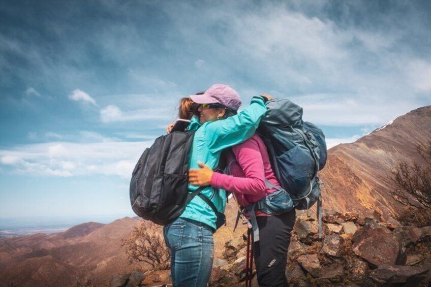 Two hikers embracing with backpacks on a mountain trail. 3