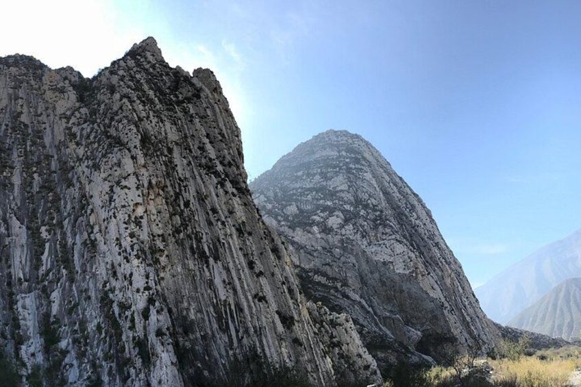 A rugged mountain landscape with a prominent rocky peak and a smaller hill in the background. 1