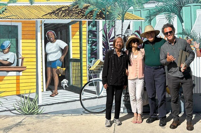 Un gruppo di persone davanti a una casa colorata, con una bicicletta e un cane. 2