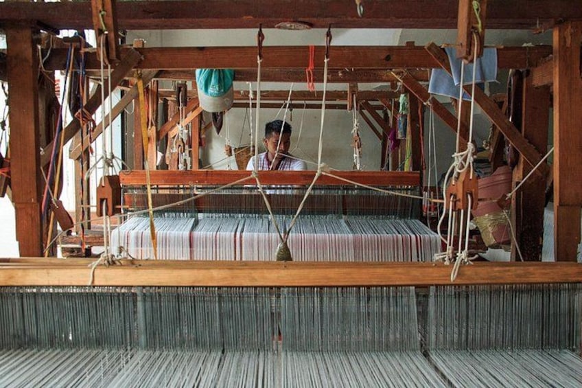 A traditional weaving loom with a person operating it. 1