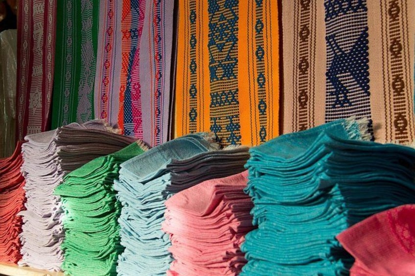 A variety of colorful woven textiles displayed in stacks. 5