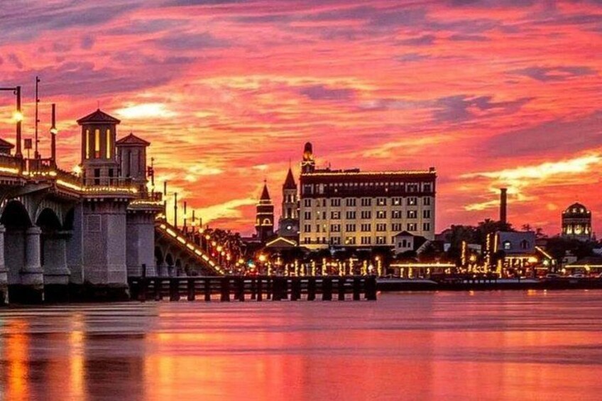 A sunset over a cityscape with a prominent bridge and a large building with a dome. 3