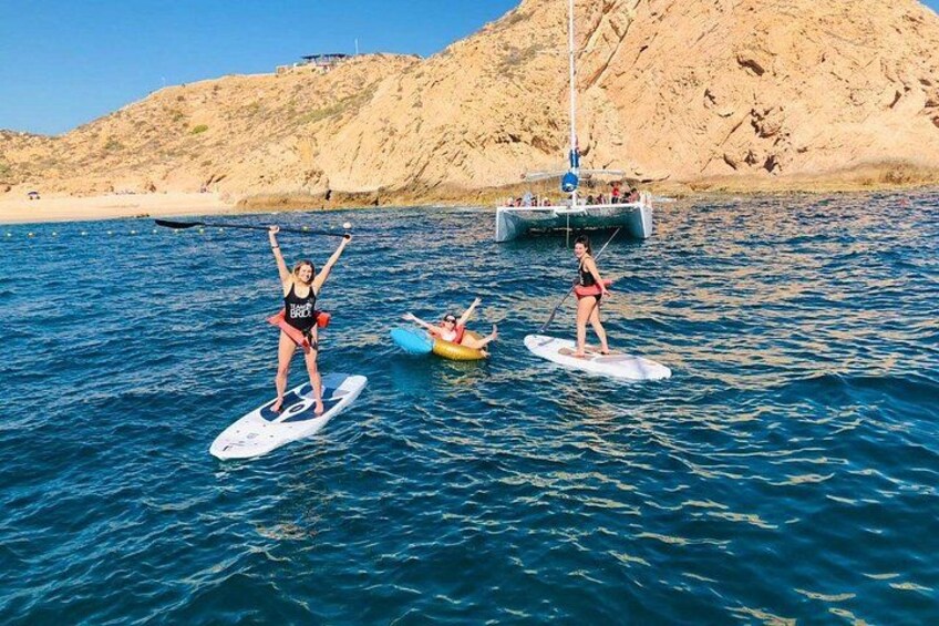 Zwei Personen auf Paddleboards im Wasser, im Hintergrund ein Segelboot. 2