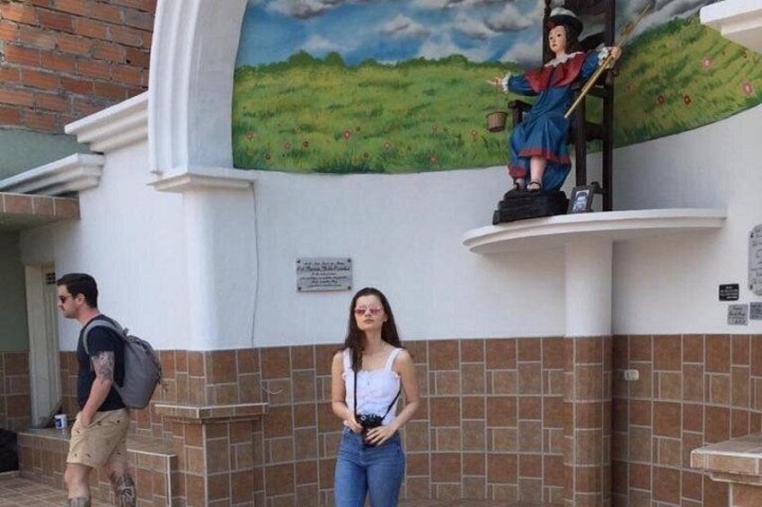 A mural of a woman in a field, a statue of a woman on a pedestal, and a brick wall with a tiled base. 3