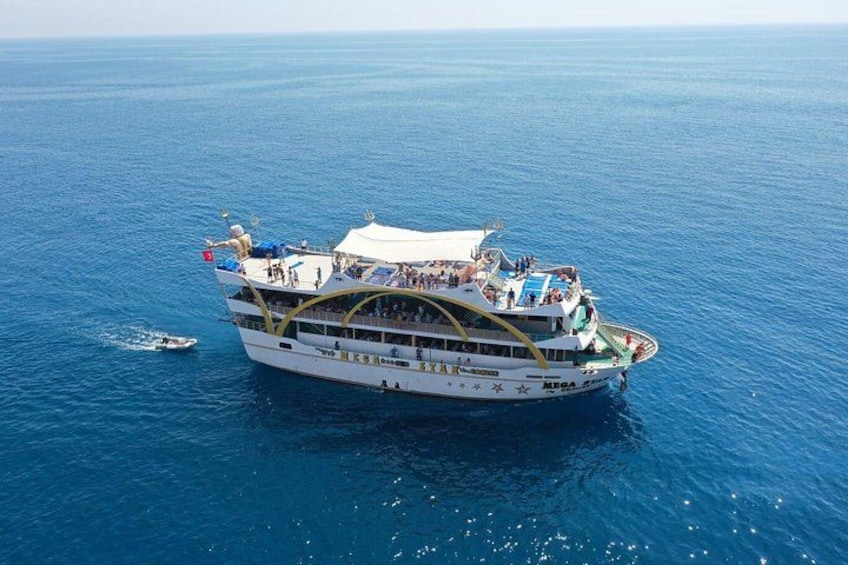 Een groot wit cruiseschip met meerdere dekken, waarop passagiers van het uitzicht genieten. 4