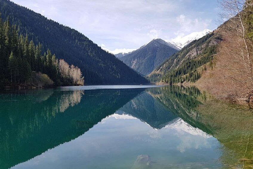 A calm lake surrounded by mountains and dense forests. 5