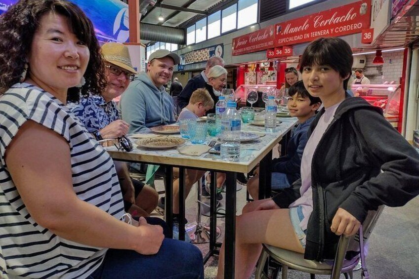 A group of people sitting at a table in a restaurant with a menu in the background. 5