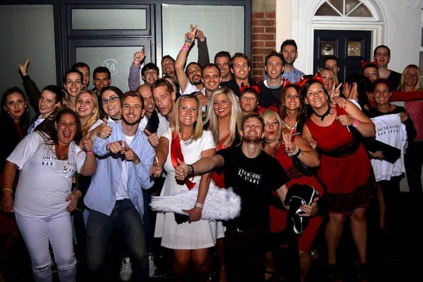 Eine Gruppe von Menschen posiert für ein Foto vor einem Gebäude mit einer Tür und Fenstern. 1