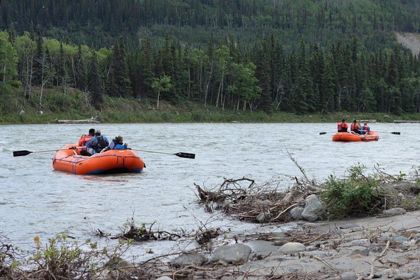 Two orange inflatable rafts on a river surrounded by forested hills. 3