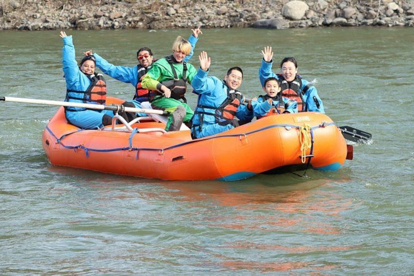 A group of people in an orange inflatable raft on a river. 2