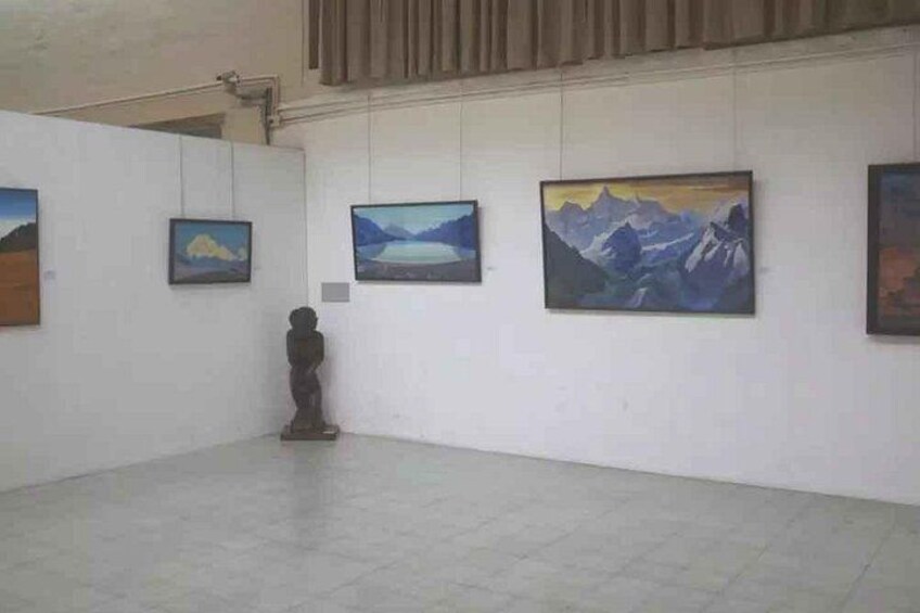 Een kunstgalerie met schilderijen aan de muren en een sculptuur in het midden. 1