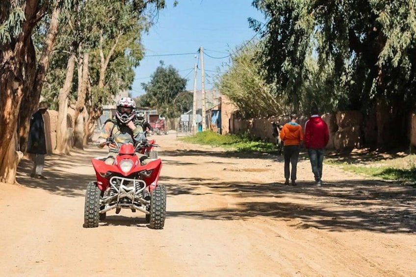 Ein Feldweg mit einem roten Quad im Vordergrund und zwei Personen, die im Hintergrund gehen. 4
