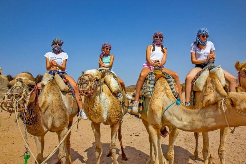 Tres personas montando camellos en un desierto. 2