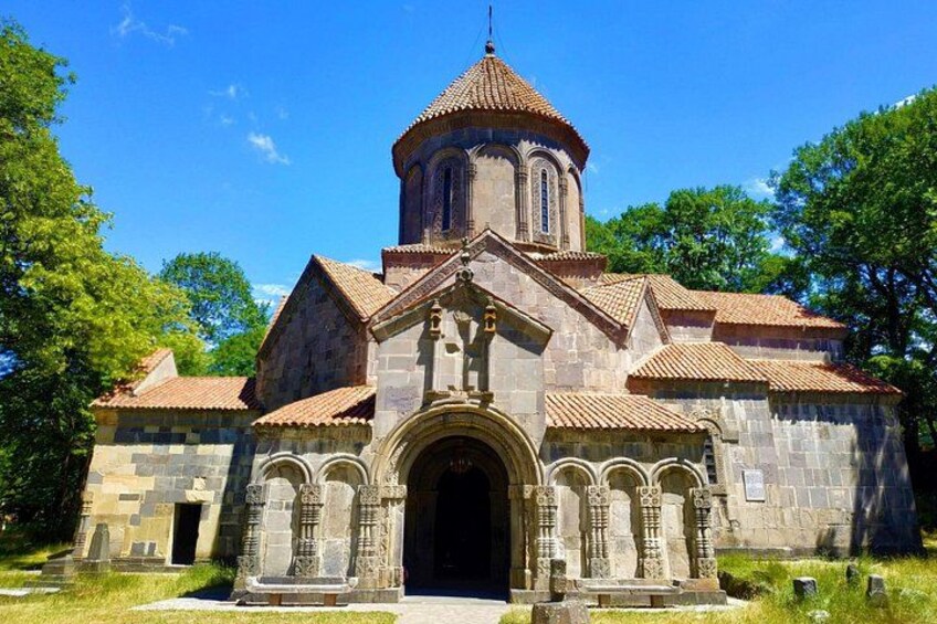 A stone church with a bell tower, arched entrance, and a tiled roof. 1