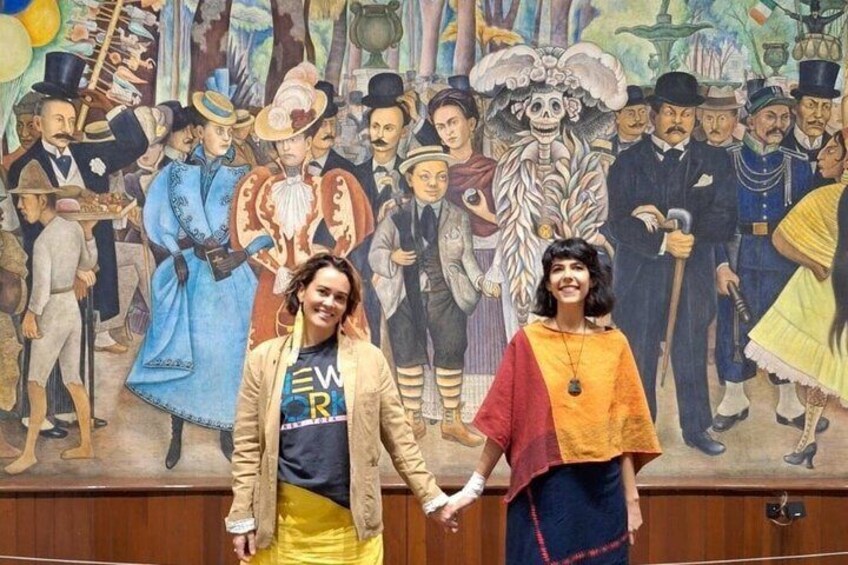 Due persone davanti a un murale raffigurante figure storiche e scheletri. 2