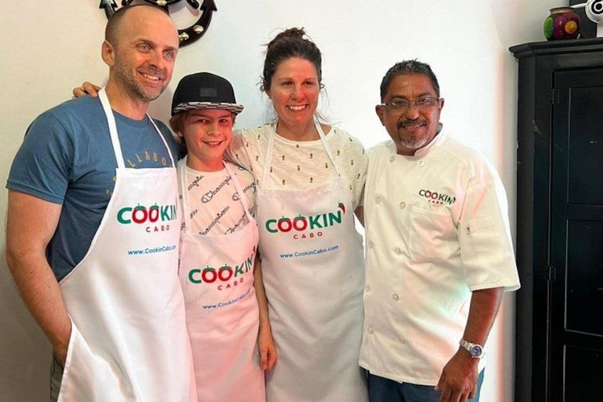 Vier personen met schorten waarop het logo 'COOKIN CABO' en een websiteadres staat. 5