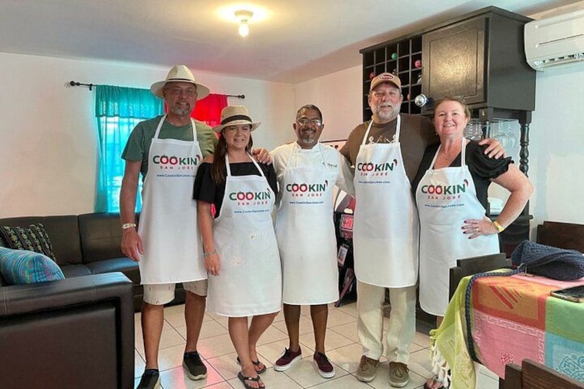 En gruppe mennesker iført forklæder med logoet 'COOKIN San Jose' i et køkkenmiljø. 2
