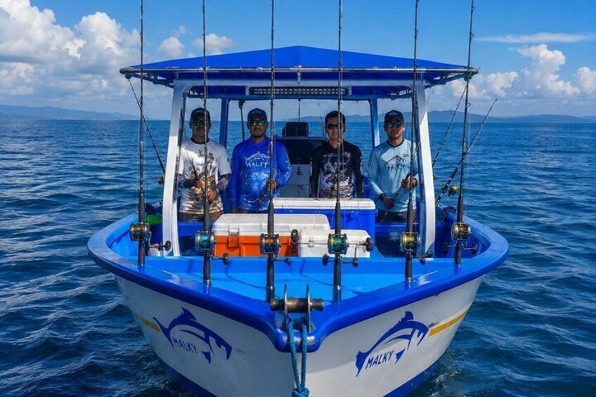 A boat with four people on a calm sea, fishing rods, and a logo on the side. 3