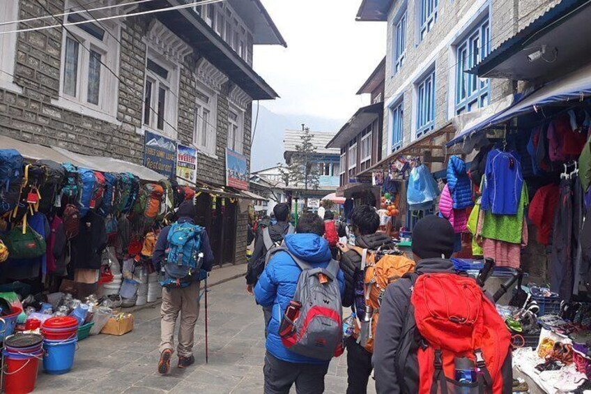 A narrow street with shops selling backpacks and outdoor gear. 5