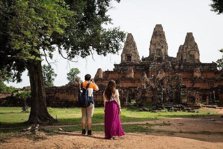 Two people standing in front of a historical temple with three tall towers. 3
