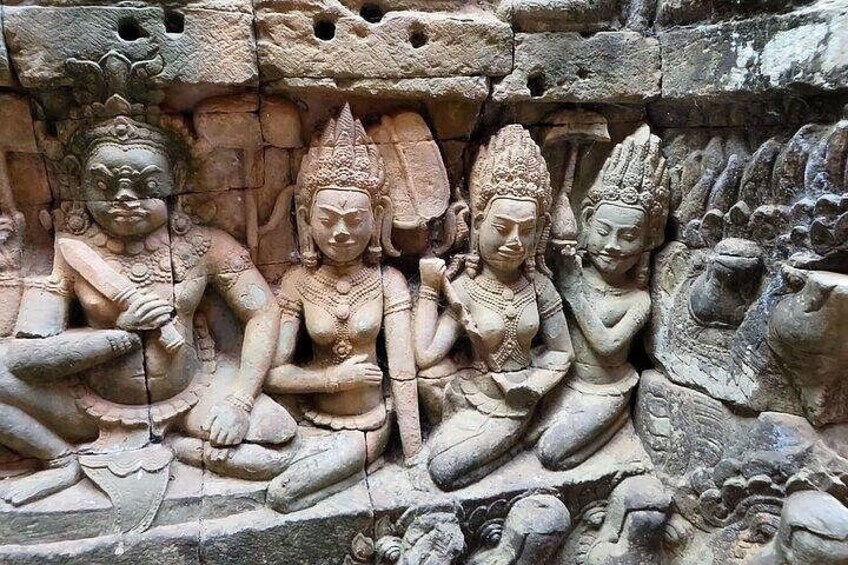 A stone carving of four seated figures with intricate details and a background of carved foliage. 2