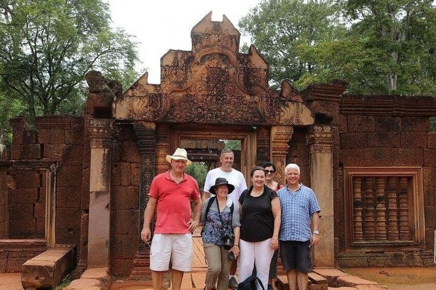 A group of people standing in front of an ornate stone structure with intricate carvings. 1