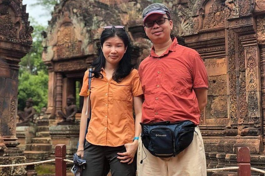 Two people standing in front of an ancient temple with intricate carvings. 4
