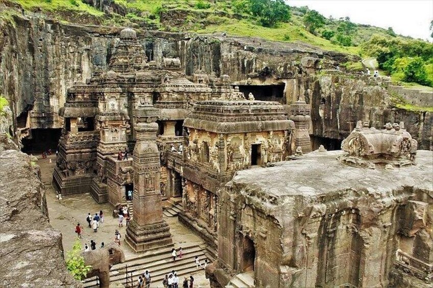 An ancient rock-cut temple complex with intricate carvings and multiple structures. 3
