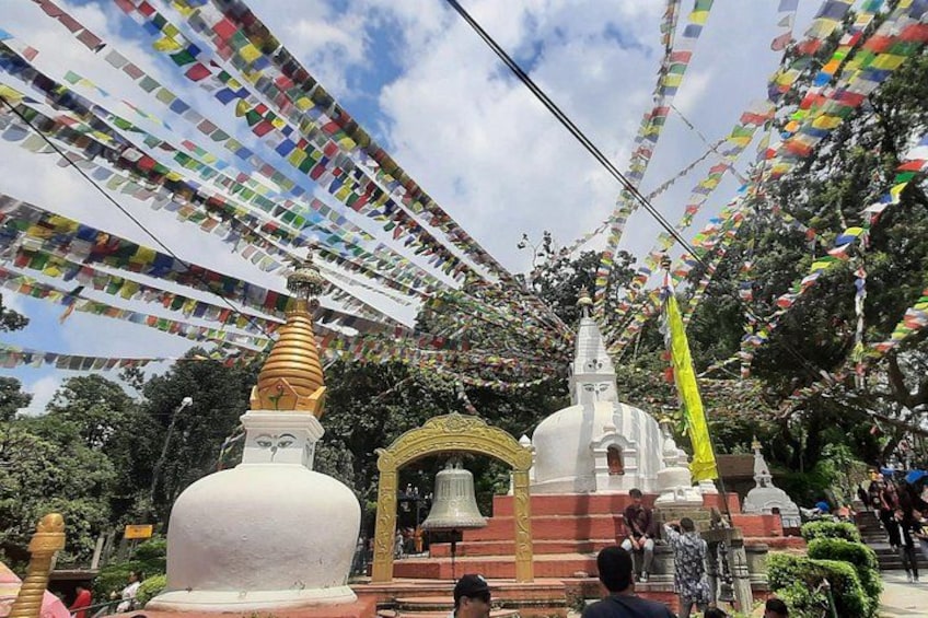 Un tempio con stupa bianche e un campanile, circondato da colorate preghiere tibetane. 1