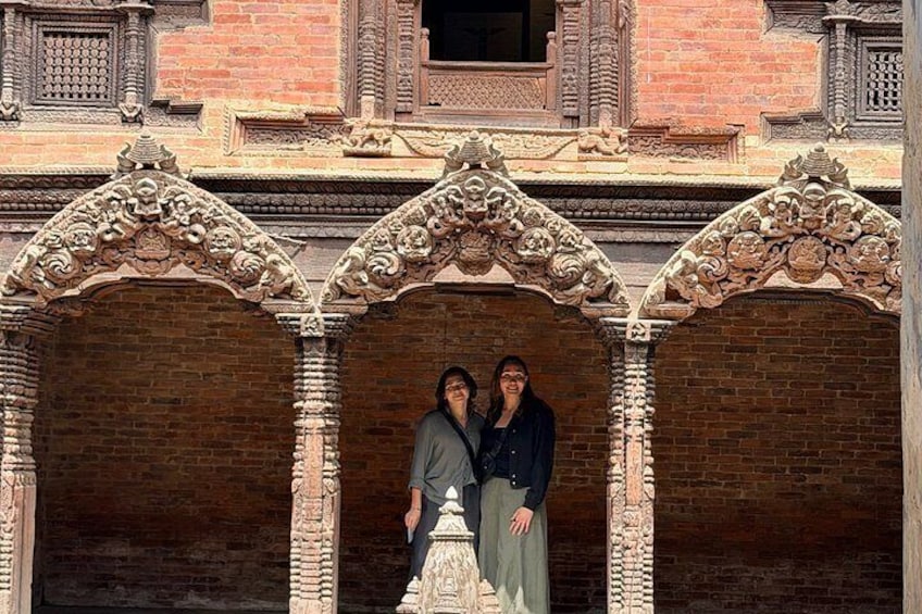 A couple standing in an ornate doorway with intricate carvings and a brick wall in the background. 3