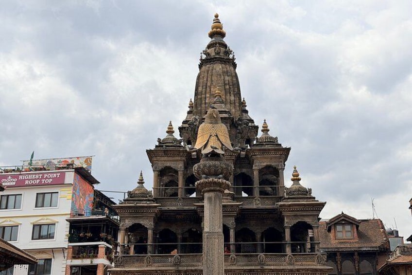 A temple with a tall spire, intricate carvings, and a large central column. 2